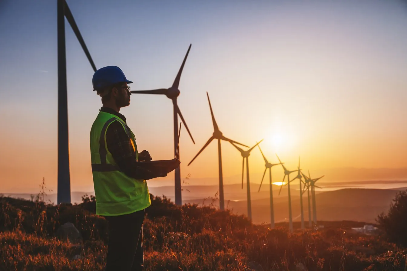 Engineer overlooking a wind farm at sunset